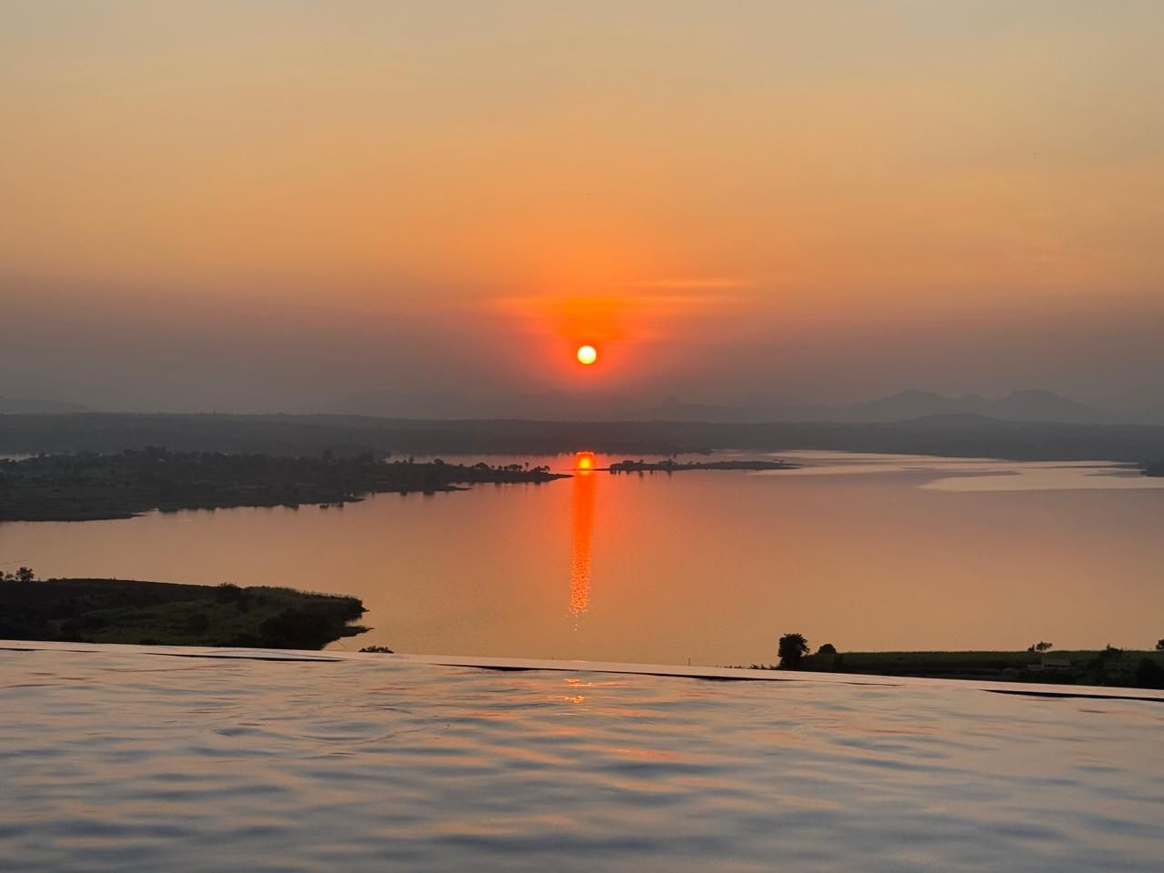 The sun setting over the lake from the pool edge