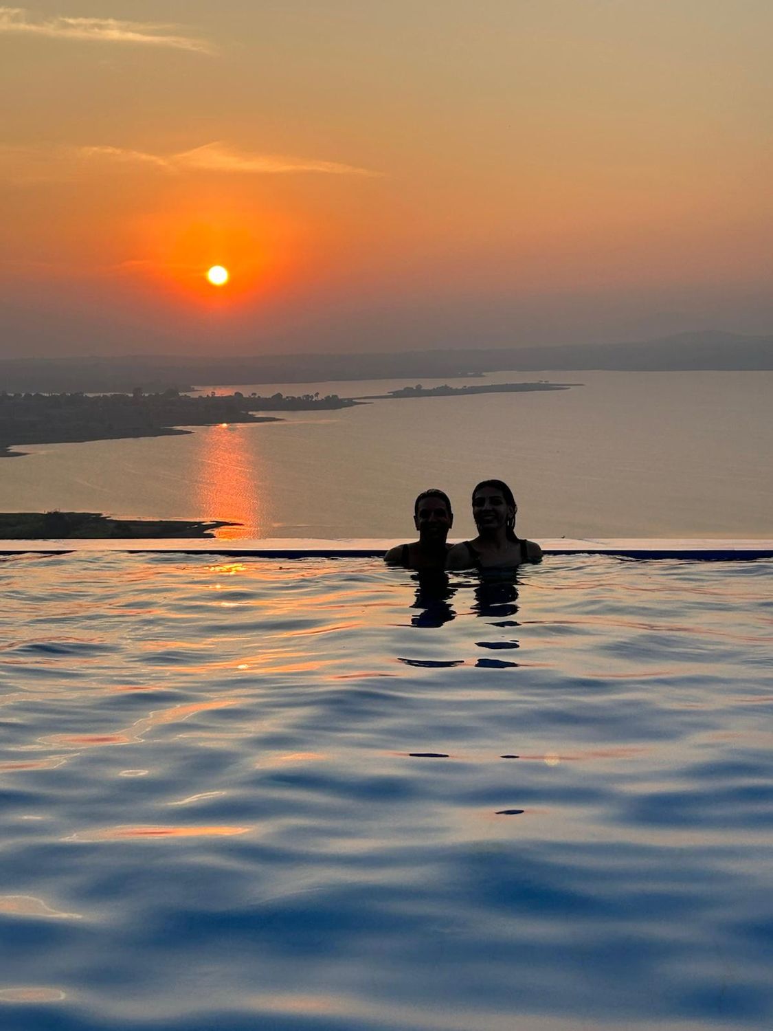 Two people in the villa's infinity pool at sunset